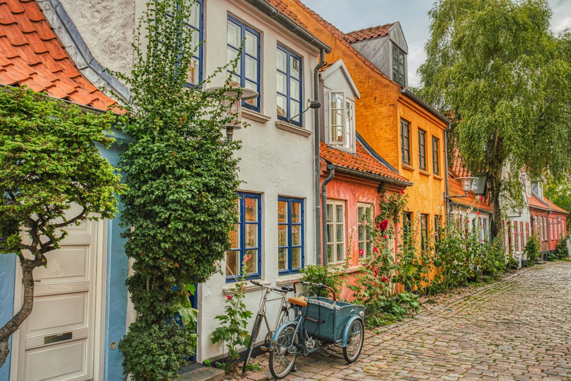 Un vélo scandinave traditionnel est garé devant une maison à la façade colorée, dans une rue piétonne pittoresque du centre-ville.