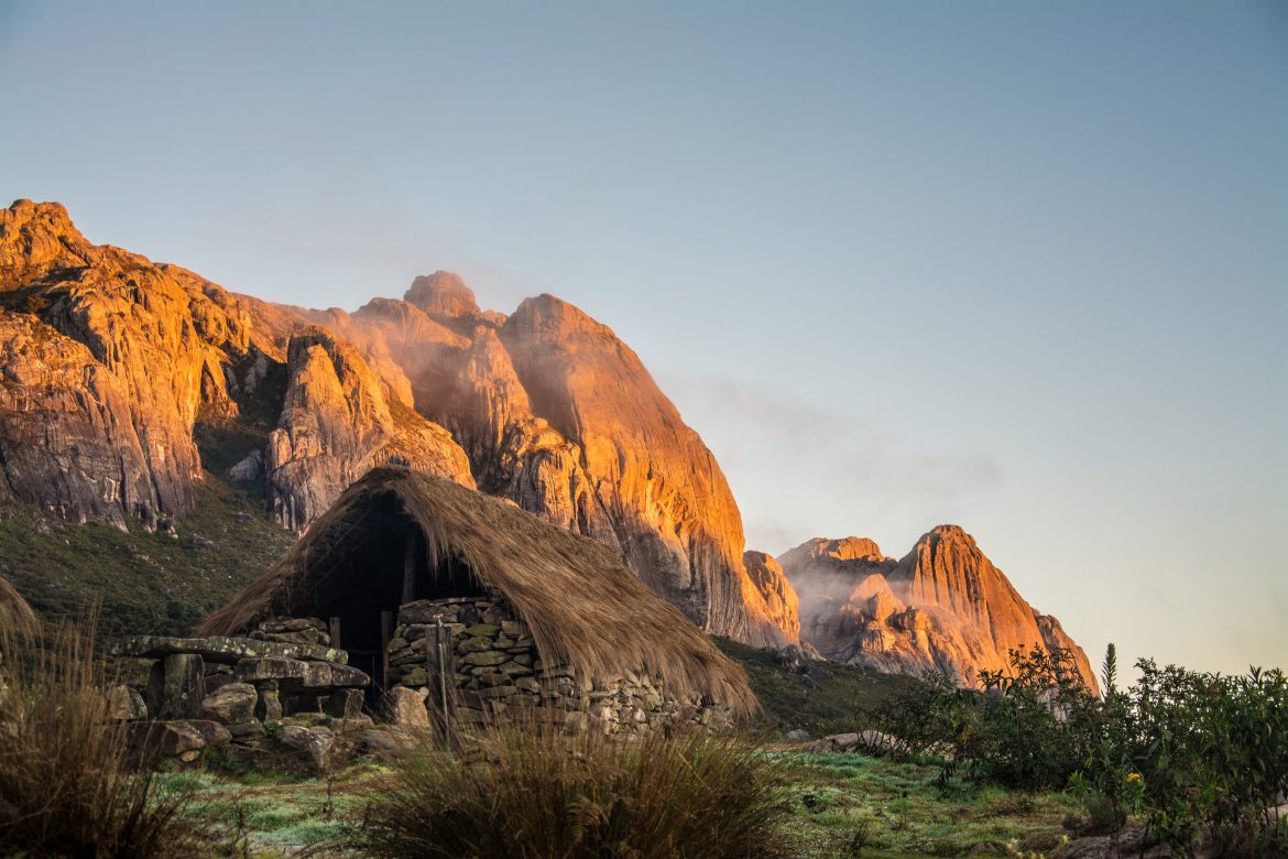 Parc national d'Andringitra au lever du soleil. Cabane en pierre au toit de chaume, montagnes rocheuses en arrière-plan, baignées par le soleil matinal. Madagascar.
