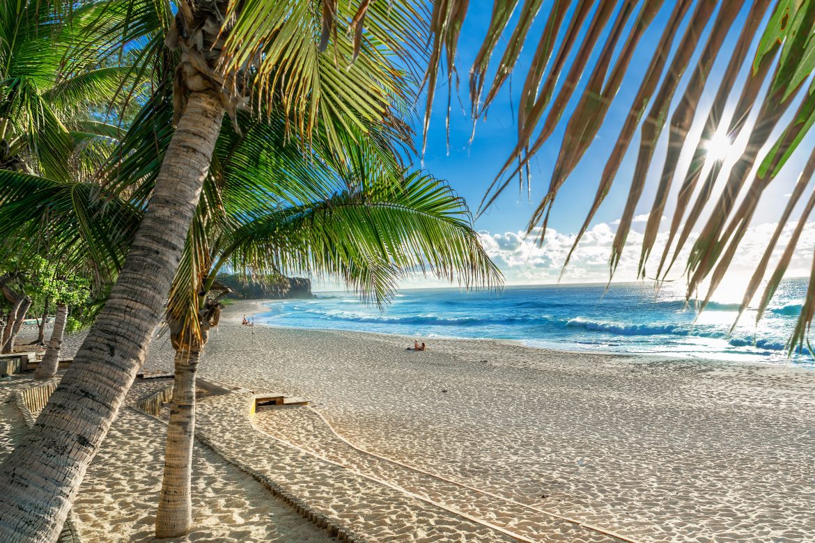 Vue panoramique du lever de soleil sur la plage de Boucan Canot, avec son eau bleue et son sable jaune à La Réunion