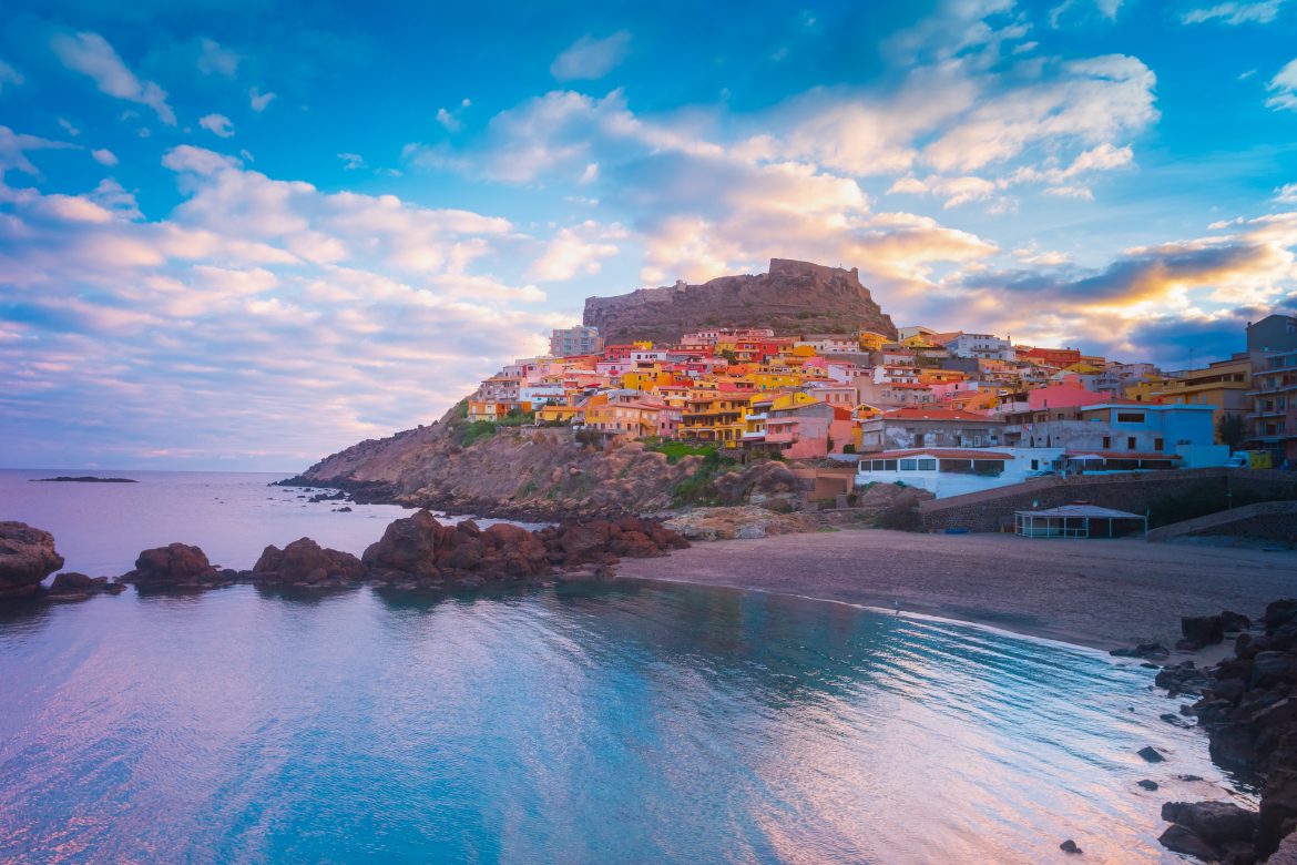 Ville de Castelsardo avec ses maisons colorées perchées sur une colline et son château médiéval qui la surplombe.