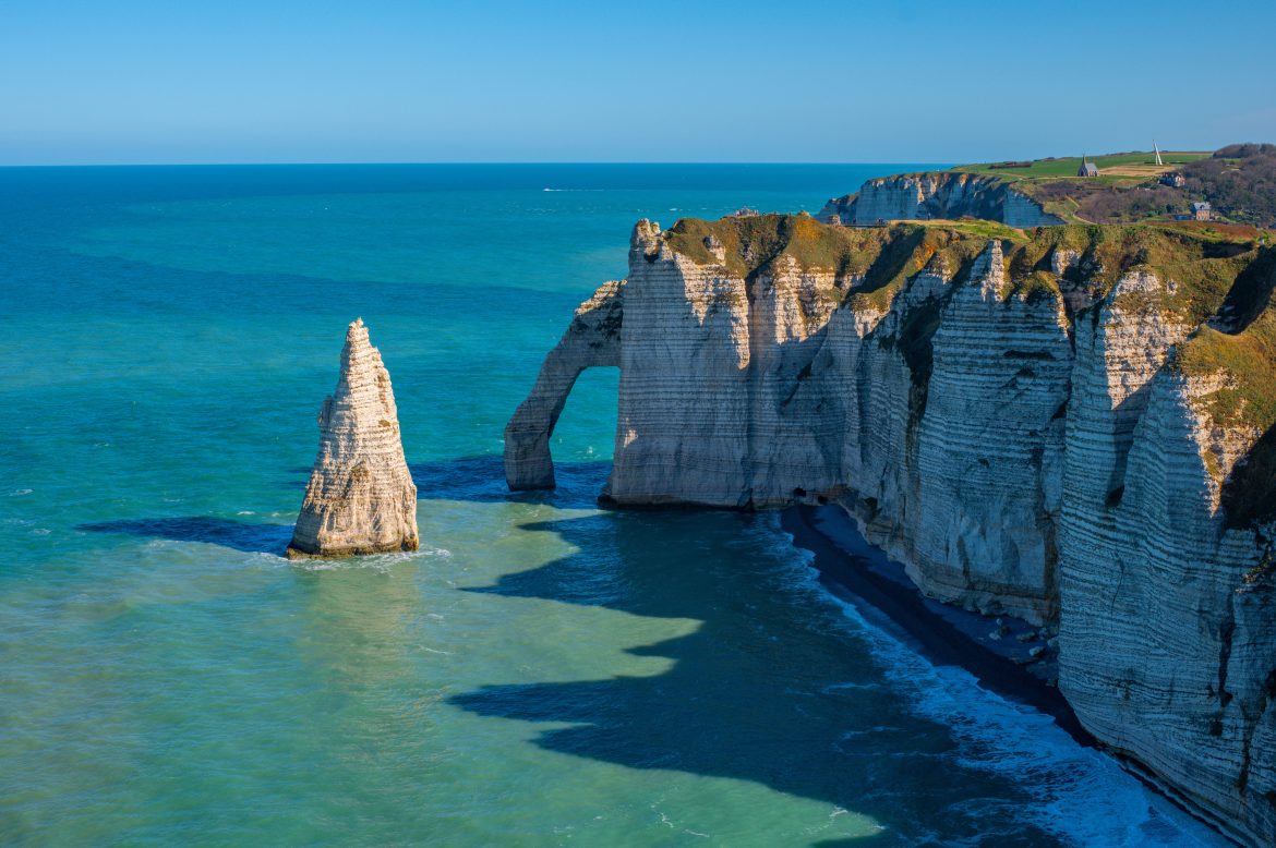 Falaises de craie ou de calcaire, arches naturelles et formation rocheuse pointue appelée l'Aiguille le long de la Manche à Étretat, en Normandie, France. Paysage marin par temps clair.