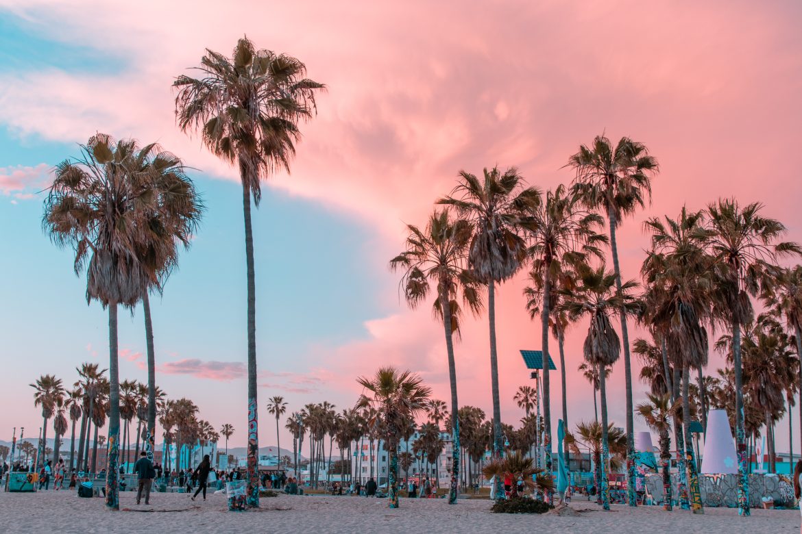 Coucher de soleil à Venice Beach, en Californie, avec des palmiers et des bâtiments.