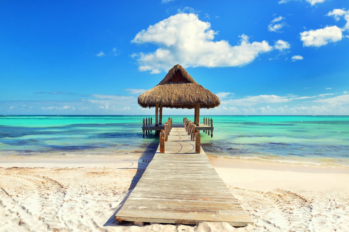 Plage tropicale de sable blanc. Jetée en bois couverte de palmes avec un kiosque sur la plage. Traitement croisé. Punta Cana, République dominicaine