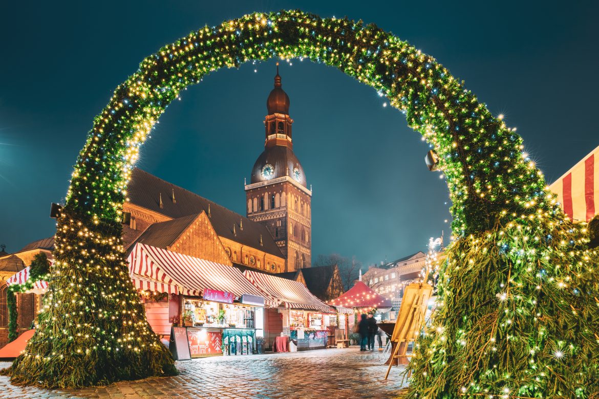 Riga, Lettonie. Marché de Noël traditionnel sur la place du Dôme, avec la cathédrale du Dôme de Riga. Monument emblématique illuminé par les fêtes de fin d'année.