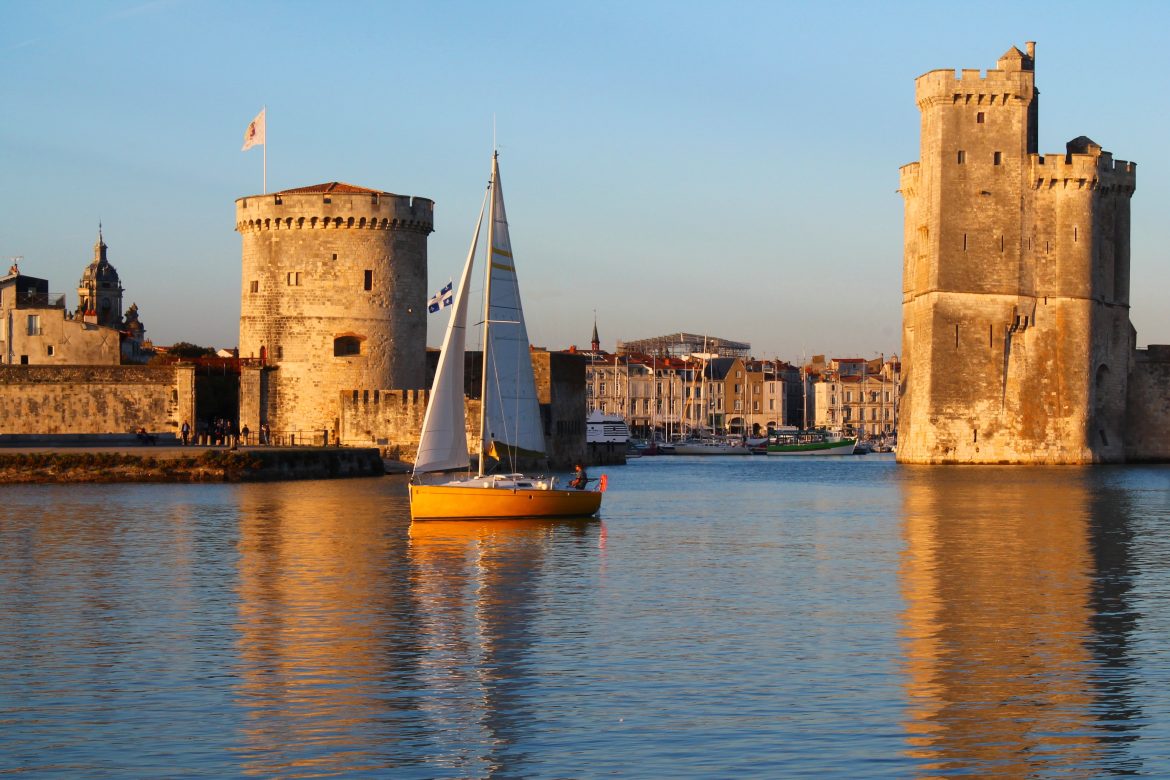 la_rochelle Port de La Rochelle au couché du soleil avec un voilier.
