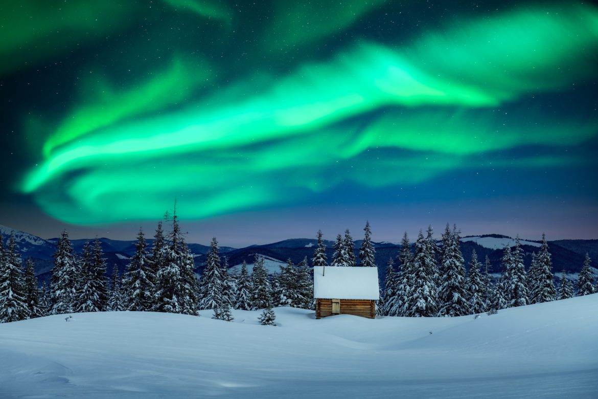 Fantastic landscape with northen light Paysage hivernal fantastique avec une maison en bois dans des montagnes enneigées et des aurores boréales dans le ciel nocturne de la Laponie Suédoise.