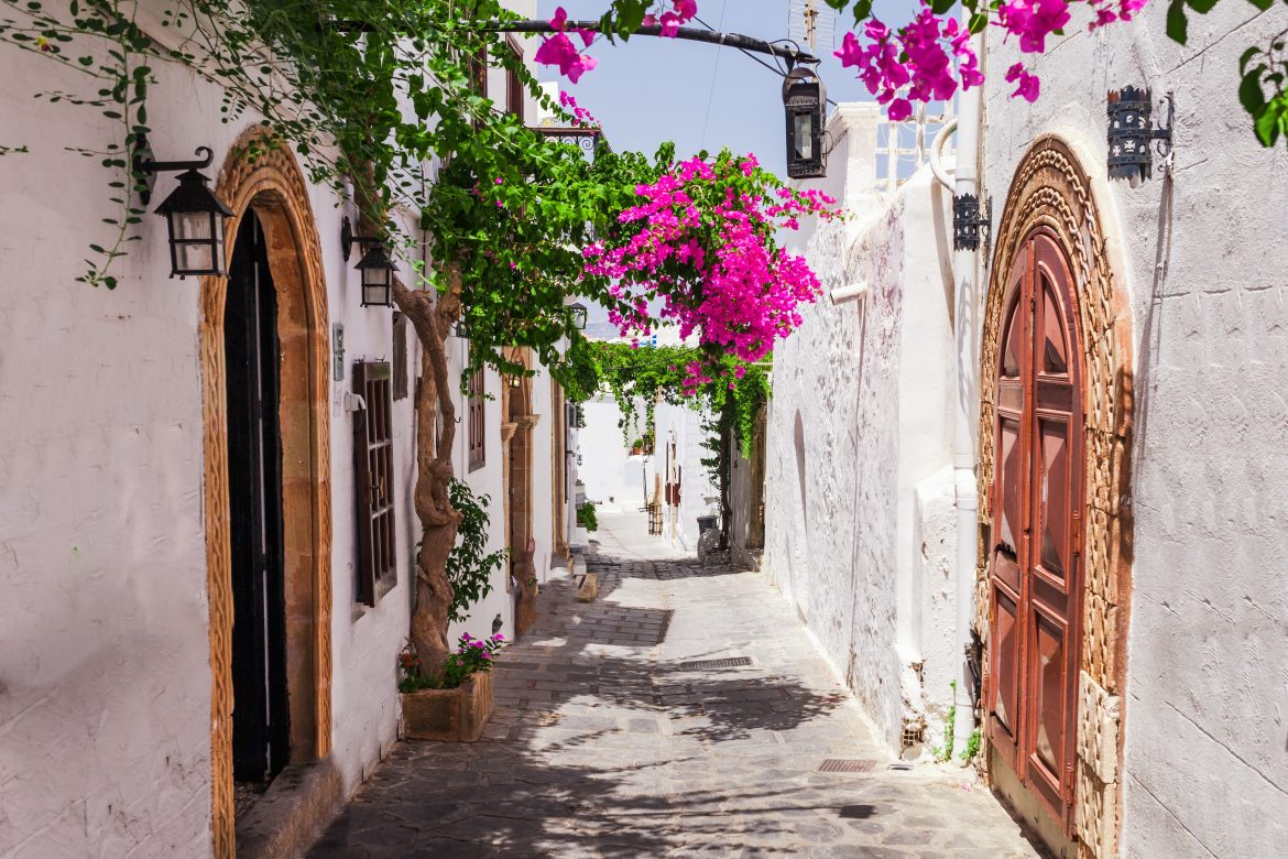 Rue étroite de Lindos, ville de l'île de Rhodes, dans le Dodécanèse, en Grèce. Belles et anciennes maisons blanches fleuries. Destination touristique réputée du sud de l'Europe.