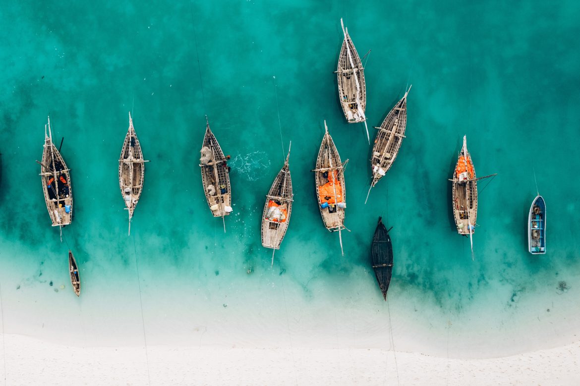 Vue aérienne de l'île de Zanzibar, en été, avec ses eaux cristallines, sa plage de sable blanc et ses pirogues à longue queue.